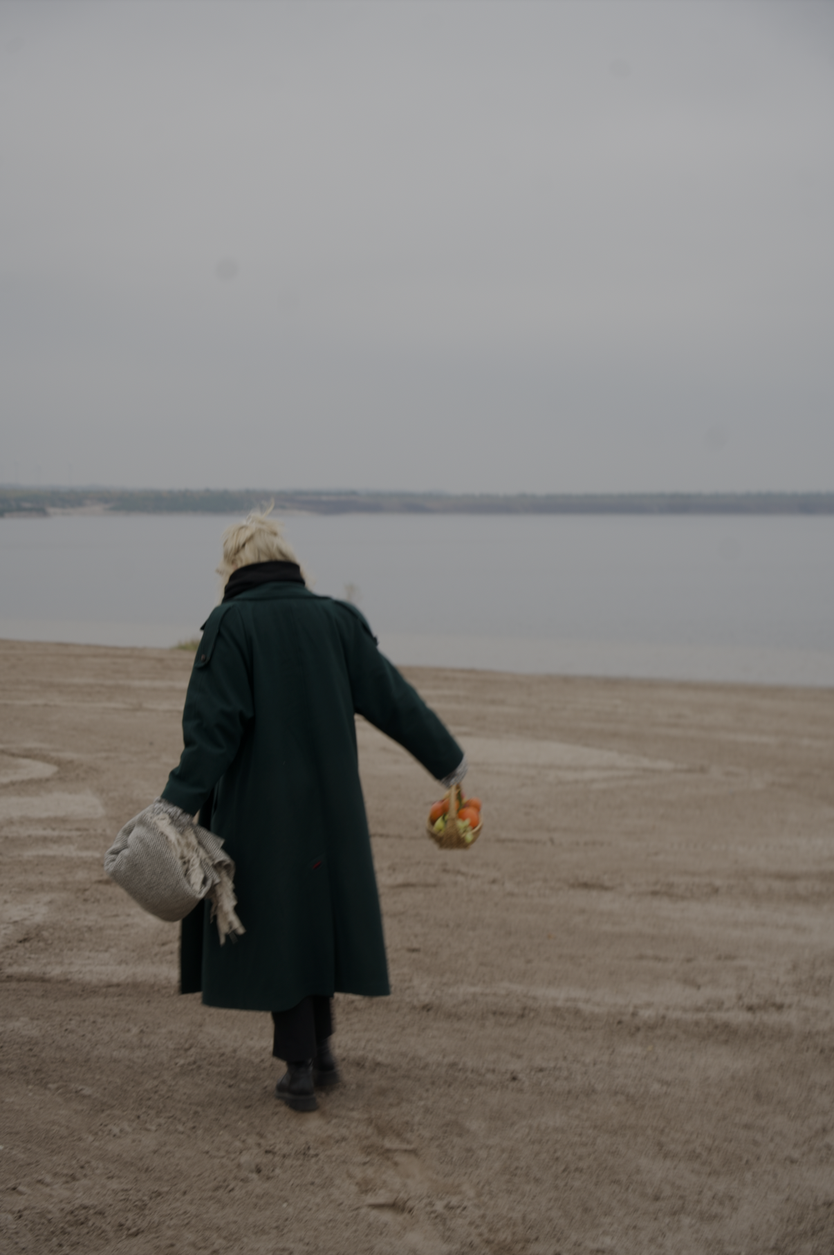 Futopia 2 Jemand geht mit einer Picknick Decke und einem Obstkorb am Strand eines kleinen Sees in der Nähe von Berlin lang